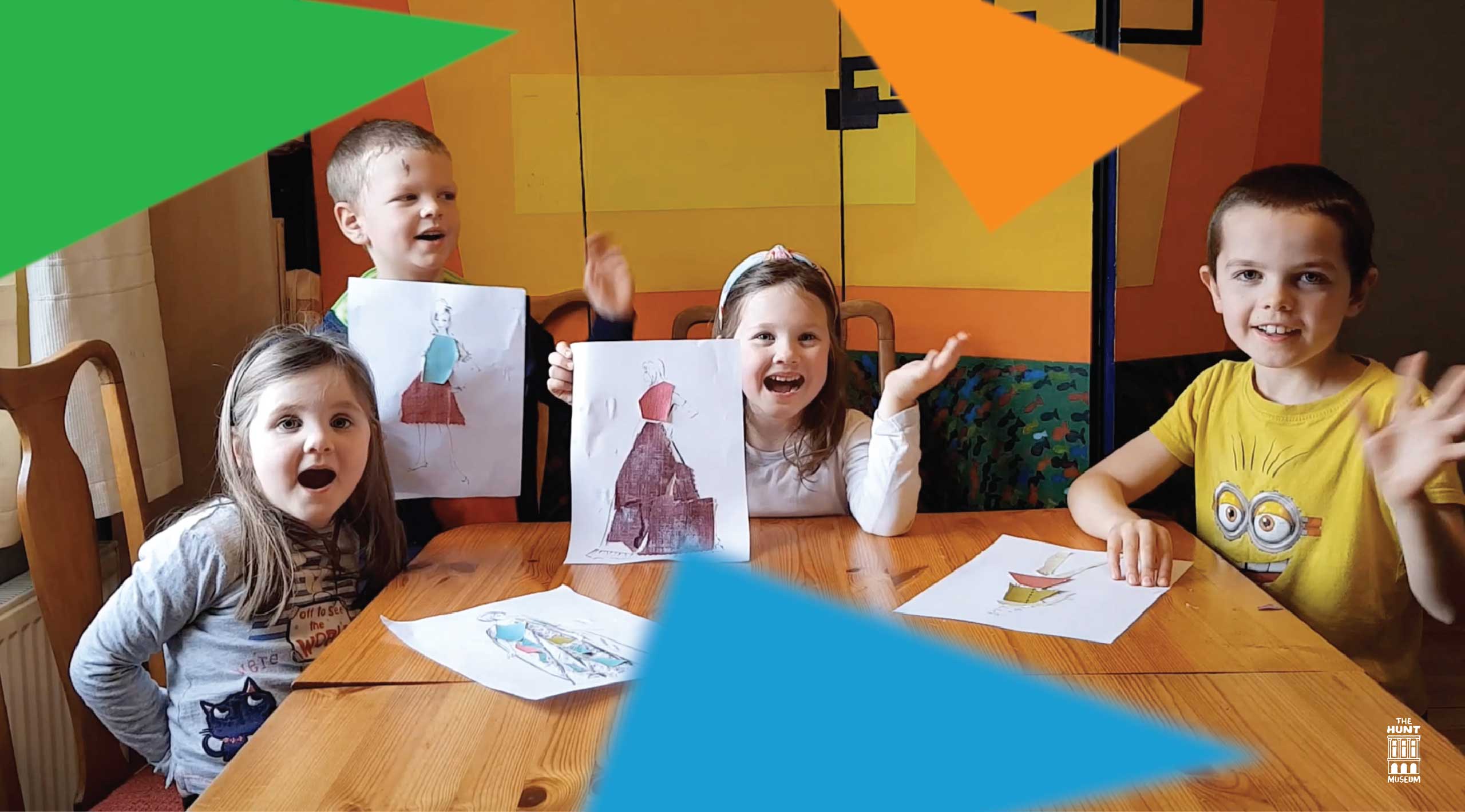 Sybils Sketchbook. 4 children wave at the camera and hold up pieces of paper with. their costume design on it